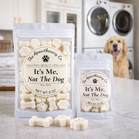 Two packages of 'It's Me, Not The Dog' wax melts with a dog in the background.