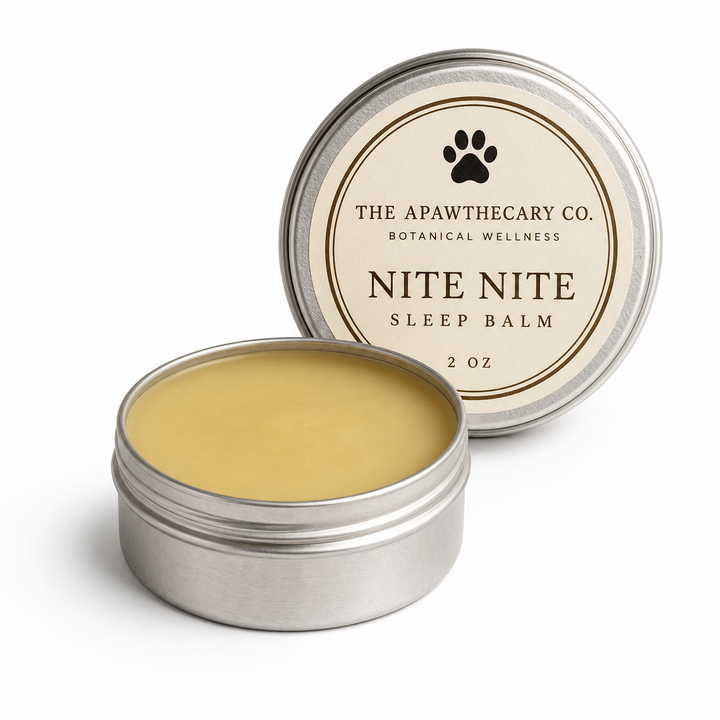 An open round silver tin of Nite Nite Sleep Balm by The Apawthecary Co. shows the pale yellow balm inside, with the lid leaning behind it on a clean white background.