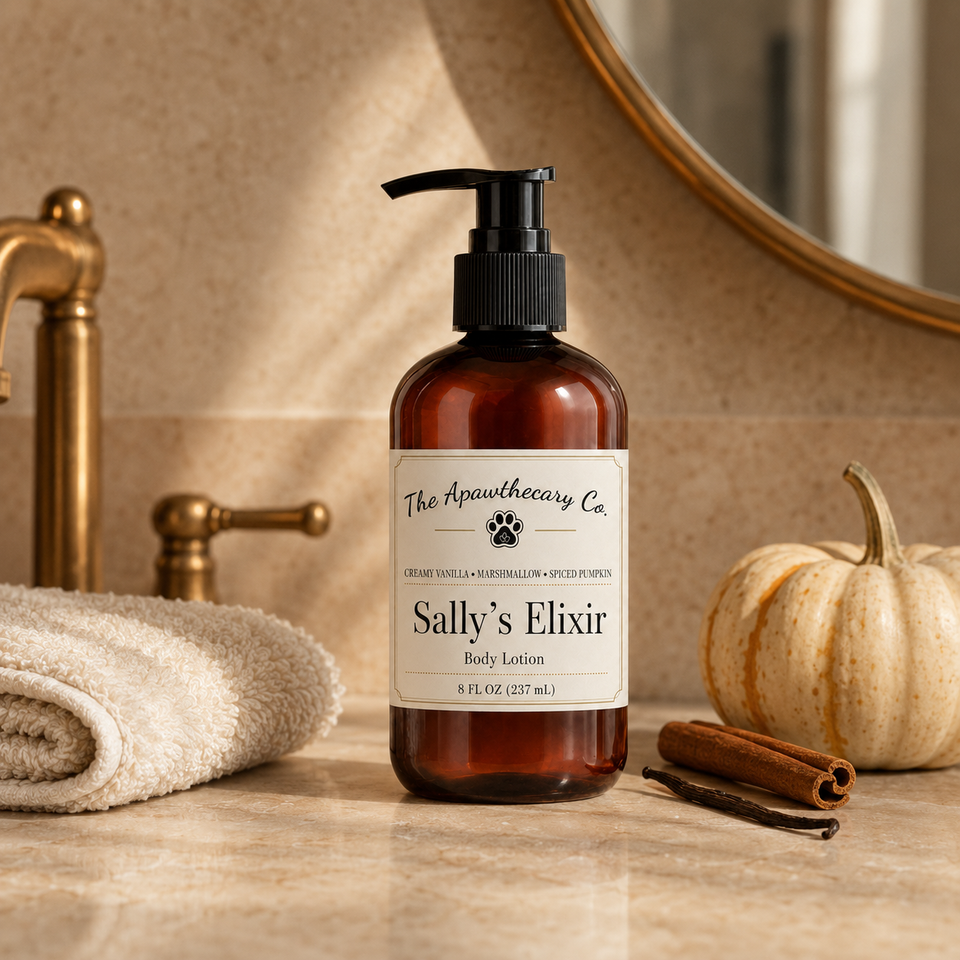 A bottle of 'Sally's Elixir' body lotion by 'The Apothecary Co.' stands on a bathroom counter next to a rolled towel, cinnamon sticks, a small pumpkin, and a brass faucet.