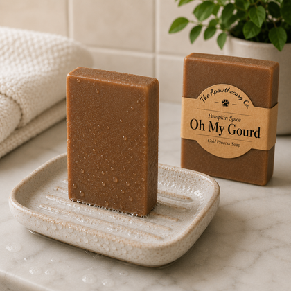 A bar of brown pumpkin spice cold process soap stands upright on a speckled soap dish next to its kraft paper packaging box. The box features a paper label that reads 'The Apothecary Co.