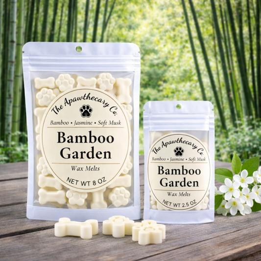 Two packages of 'Bamboo Garden' wax melts from The Apawthecary Co. on a wooden surface with bamboo and flowers in the background.
