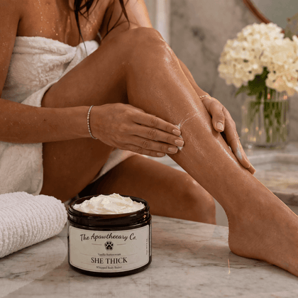 Woman applying She Thick Whipped Body Butter on her legs, showcasing the luxurious body moisturizer.