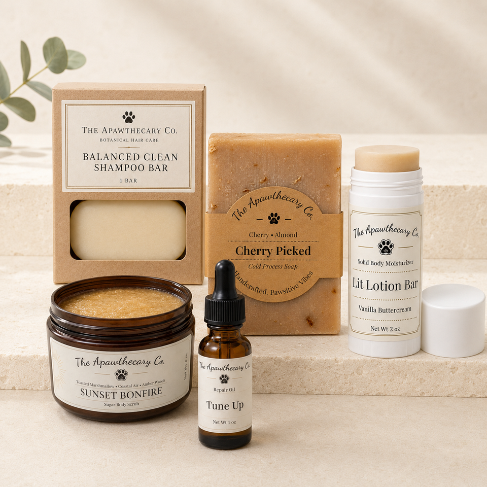 A curated set of pet grooming products from The Apothecary Co. arranged on a light beige stone surface.