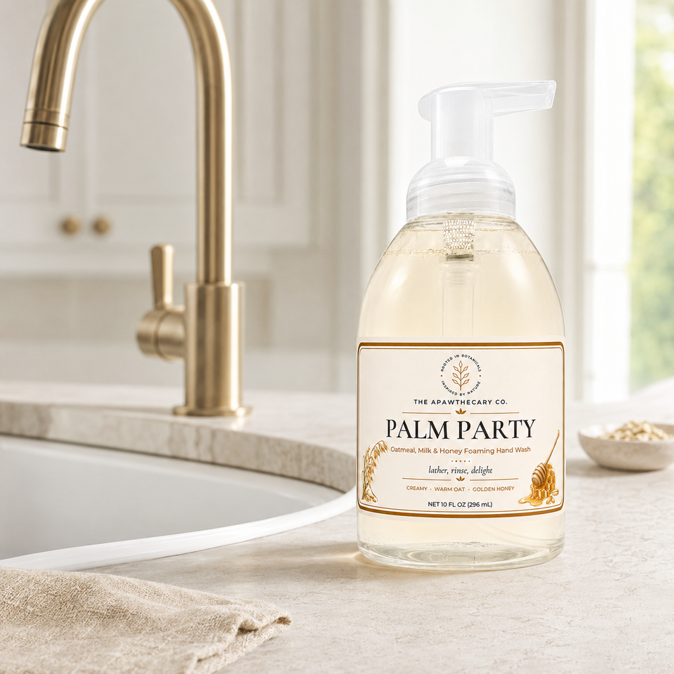 A bottle of Palm Party hand wash liquid soap with a pump dispenser sits on a light stone countertop next to a gold faucet in a bright kitchen setting.