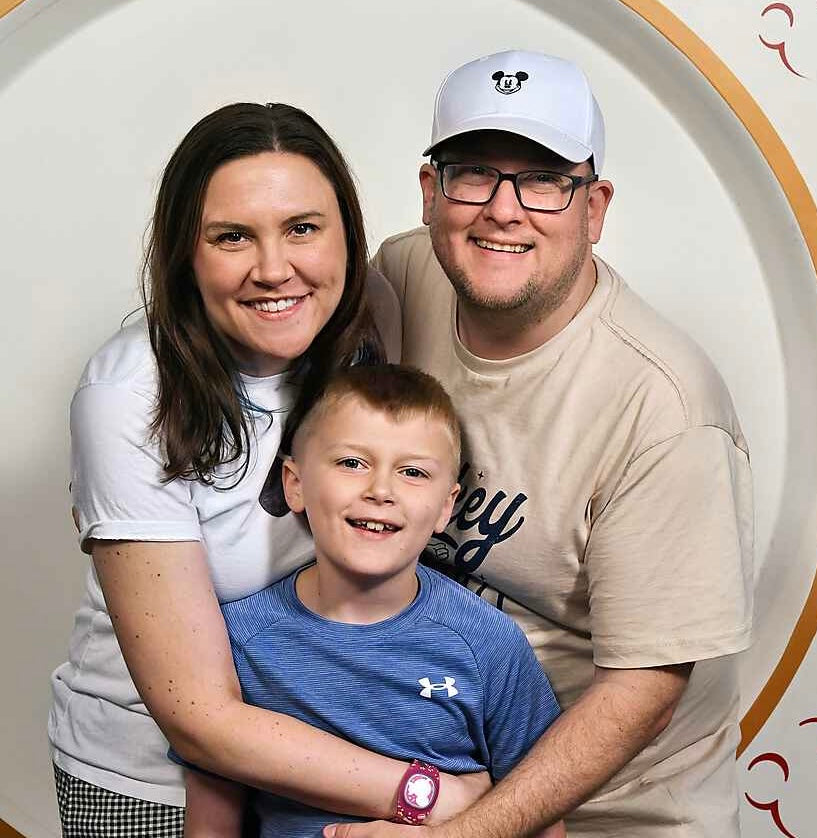 Family of three posing together with a decorative background