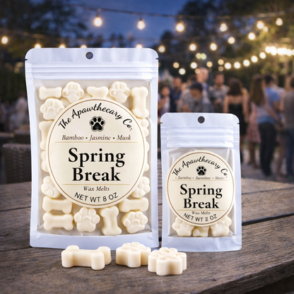 Two packages of 'Spring Break' wax melts from The Apawthecary Co. on a wooden surface with a blurred outdoor background.