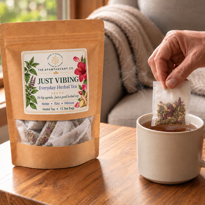 Just Vibing 15-bag herbal tea pouch beside a steaming cup as a filled tea bag is steeped.