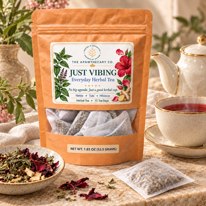 Just Vibing – Everyday Herbal Tea — Just Vibing pouch beside fine ceramic teaware on warm stone with restrained sage and dusty rose accents.