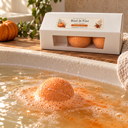 Orange Rest in Fizz Pumpkin Spice bath bomb fizzing in bathwater, with its labeled three-pack box on the tub ledge.