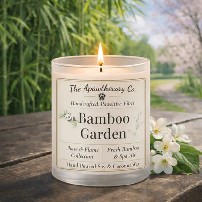 Candle labeled 'Bamboo Garden' from The Apawthecary Co. on a wooden surface with a natural background.