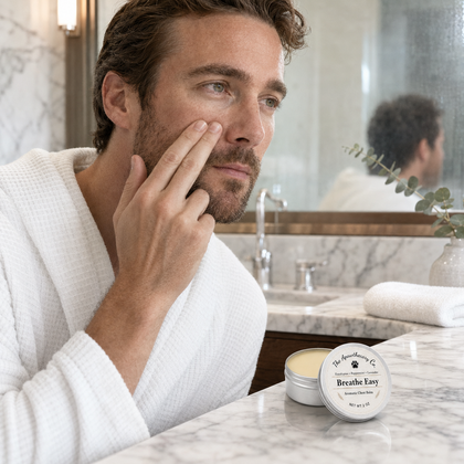 Man in a bathrobe beside an open tin of Breathe Easy aromatic balm on a bathroom counter.