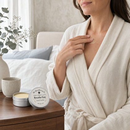 Woman touching her chest beside two tins of Breathe Easy aromatic balm on a bedside table.