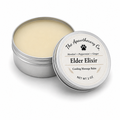 An open round silver tin of Elder Elixir Cooling Massage Balm by The Apawthecary Co., showing the light beige balm inside, with the lid leaning against it on a white background.