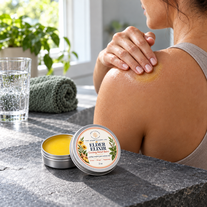 Palm-sized Elder Elixir 2 oz balm tin beside an adult applying balm to a shoulder.