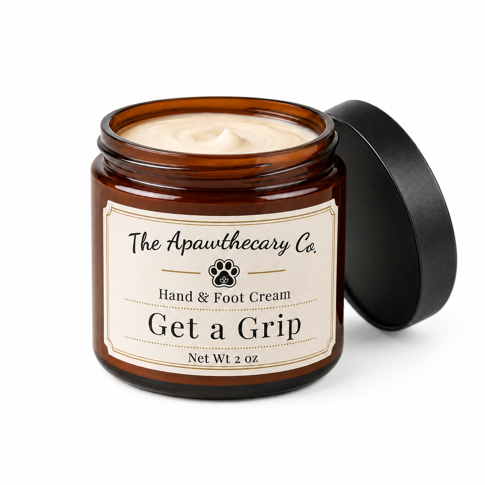 An amber glass jar of The Apawthecary Co. Get a Grip Hand & Foot Cream with its black lid leaning against it, set against a plain white background.
