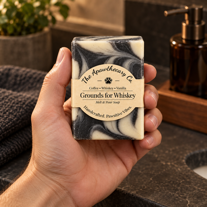 Grounds for Whiskey soap held in hand in a dark stone bathroom