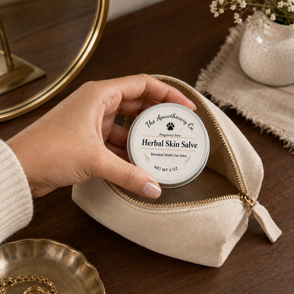 Hand placing Herbal Skin Salve into an open beige canvas pouch.