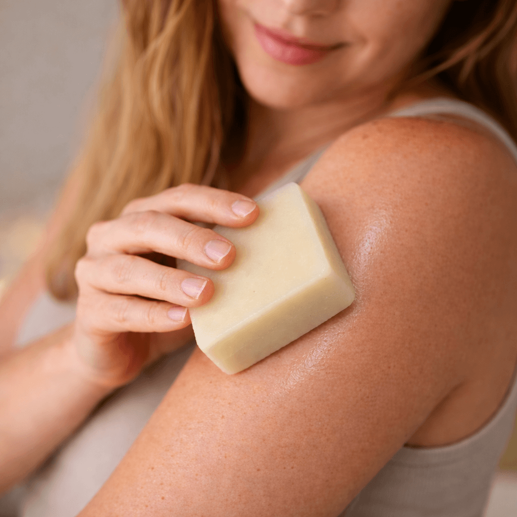 Woman applying soap to her arm with a neutral background