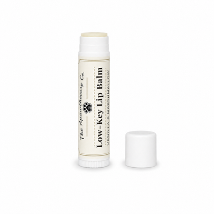 Low-Key Lip Balm tube in vanilla and marshmallow with its cap beside it on a white background.