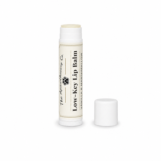Low-Key Lip Balm tube in vanilla and marshmallow with its cap beside it on a white background.