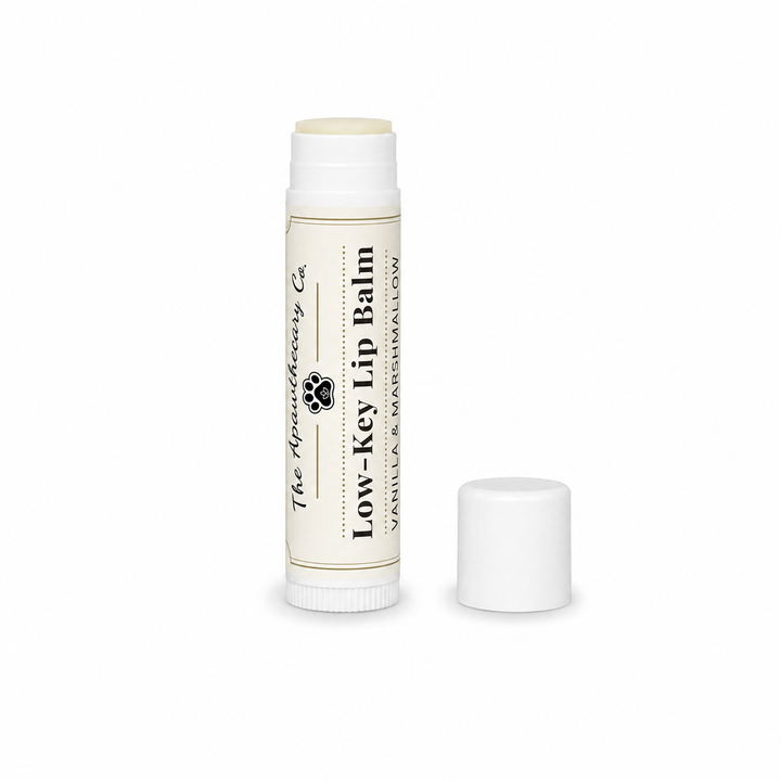 Low-Key Lip Balm tube in vanilla and marshmallow with its cap beside it on a white background.