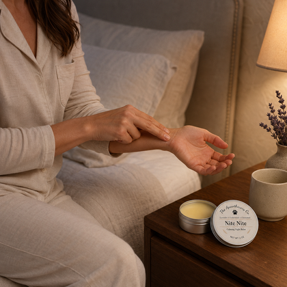 Person applying Nite Nite balm to their forearm beside the open tin on a bedside table.