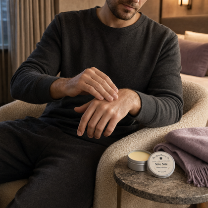 Man applying Nite Nite balm to his hand beside the tin in a softly lit room.