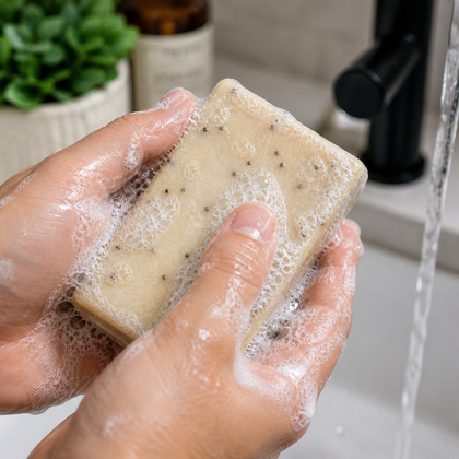 Hands holding Pulp Friction - Standard Cold Process Soap - Exfoliating Citrus & Poppy lathering in water.