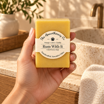 Rum With It soap held beside a warm travertine sink