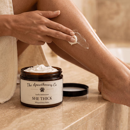 She Thick whipped body butter in an open 8 oz jar while a small amount is applied to the leg.