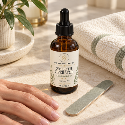 Smooth Operator 2 fl oz cuticle and nail oil beside a nail file and hand on a light stone surface.