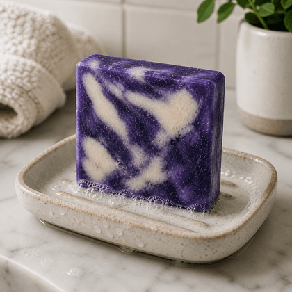 Purple and white soap bar on a textured soap dish with a marble background