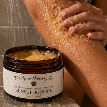 User applying Sunset Bonfire Sugar scrub on arm, highlighting exfoliating texture of body scrub.