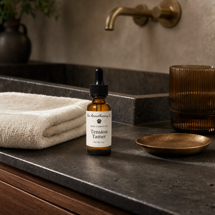 Tension Tamer oil bottle on a dark stone counter beside a folded towel and brass faucet.